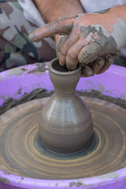 Hands of a potter, creating an earthen jar on the circle.