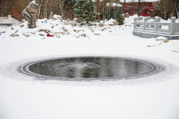 istock Circular frozen pond surrounded by Asian architecture during winter snowfall 2201270823