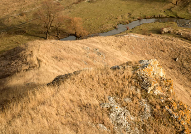 A small river flowing among prairie hills fields. An autumn landscape