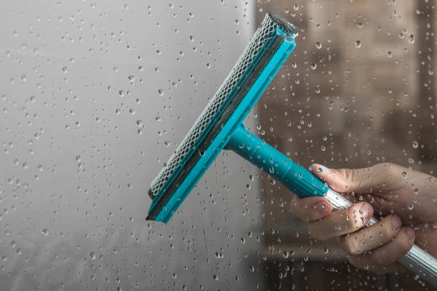 istock close up cleaning shower glass door with squeegee 2201274053