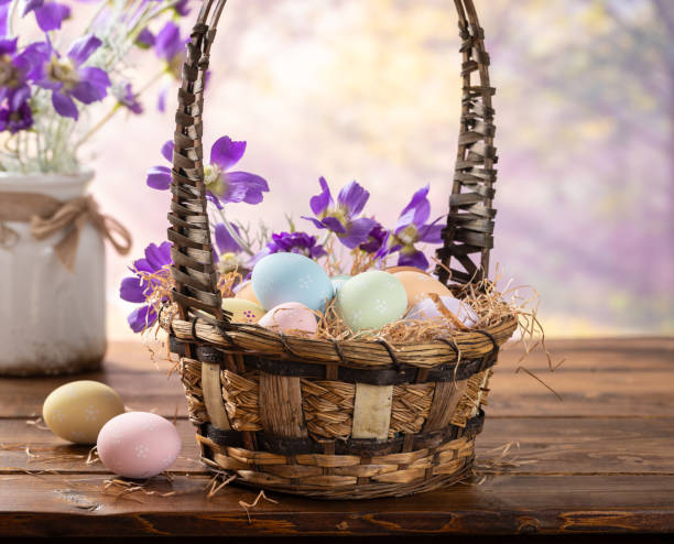 istock Easter eggs in a basket and purple daisies with vibrant spring background 2201274278