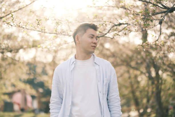 istock handsome Asian young with sakura blossom tree under sunshine 2201282149