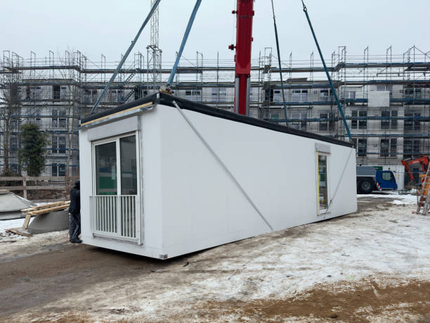 A prefabricated modular building unit being lifted by a crane at a construction site