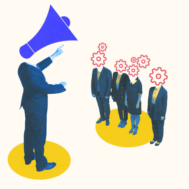 istock Conceptual art design. Business leader in suit pointing forward with head replaced by megaphone while group of employees with gear-shaped heads listens. 2201284459