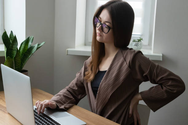 istock Tired female office worker, freelancer feeling back pain while working on computer, laptop. Symptoms of office syndrome 2201287854
