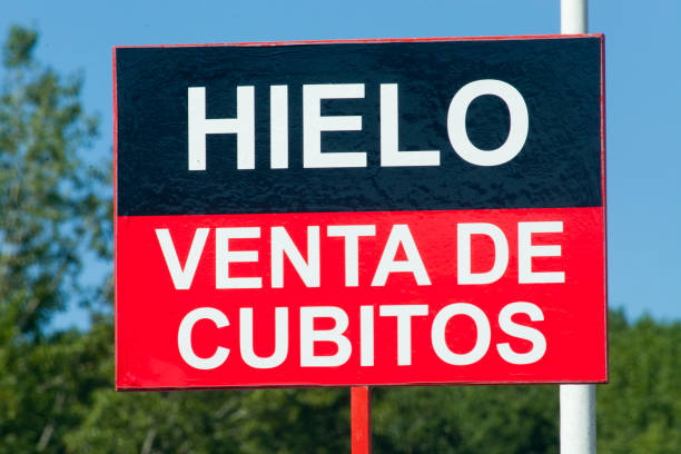 Ice cubes sale sign at roadside in spanish language. Landscape and clear sky in the background.