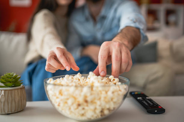 istock close up on couple hands hold popcorn from bowl on the table 2201295291