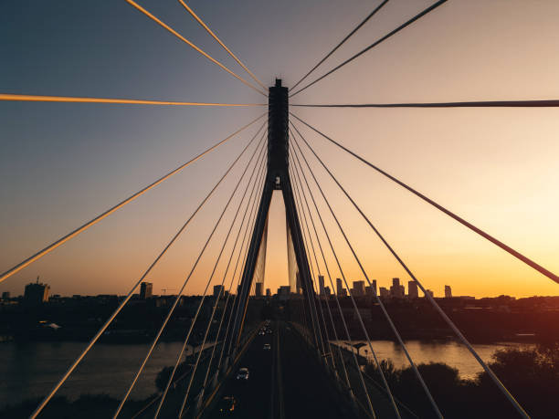modern metal cable bridge over Vistula at sunset, contemporary geometric architecture, cable-stayed bridge at city skyline, symmetry and architecture urban contrast, Warsaw. High quality photo