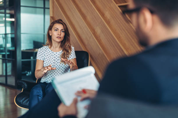 istock Young businesswoman with serious expression talking to a therapist 2201300933