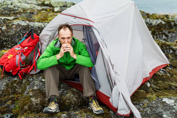 istock Mid adult man sitting in tent and drinking tea 2201309181