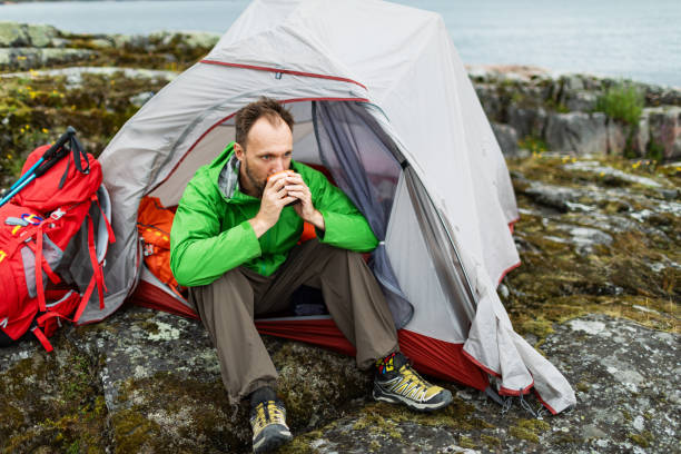 istock Mid adult man sitting in tent and drinking tea 2201309747