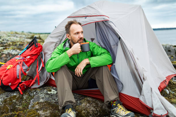 istock Mid adult man sitting in tent and drinking tea 2201309760