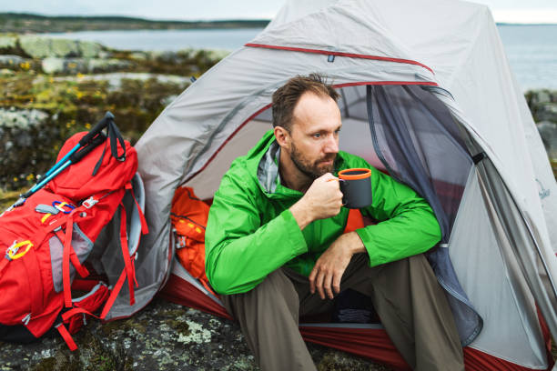 istock Mid adult man sitting in tent and drinking tea 2201309855
