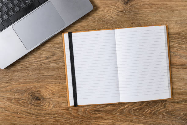 istock Open Notebook and Laptop on Wooden Desk 2201310744