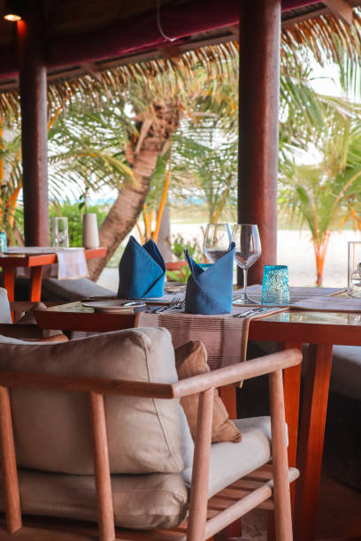 istock Elegant fine dining beach restaurant by the Sea with outdoor chairs and table setting in gourmet barefoot beach concept linen table setting and wood chairs 2201319834