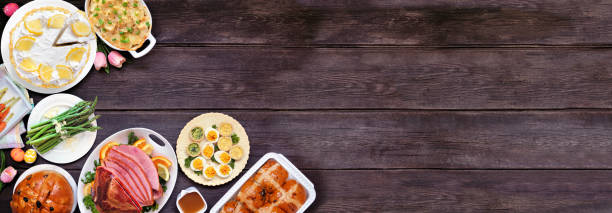 istock Classic Easter ham dinner. Overhead view corner border on a dark wood banner background with copy space. 2201320378