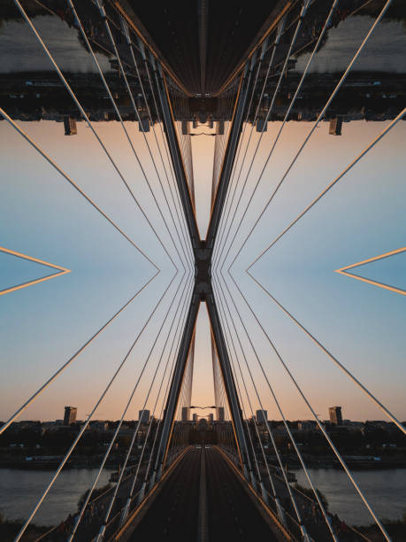 Intricate mirrored geometric lines and shapes converge in a symmetrical pattern, capturing a hi-tech abstract aesthetic against a vibrant sunset skyline.