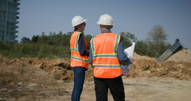 istock The project engineer team with orange safety vests  holds laptops and blueprint drawings working at the construction sideline, drainage construction 2201324522