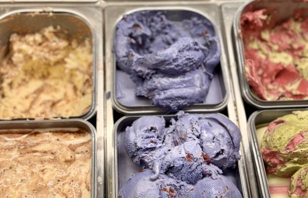 An inviting and delightful selection of colorful and various ice cream flavors is beautifully served in a display case. Close-up