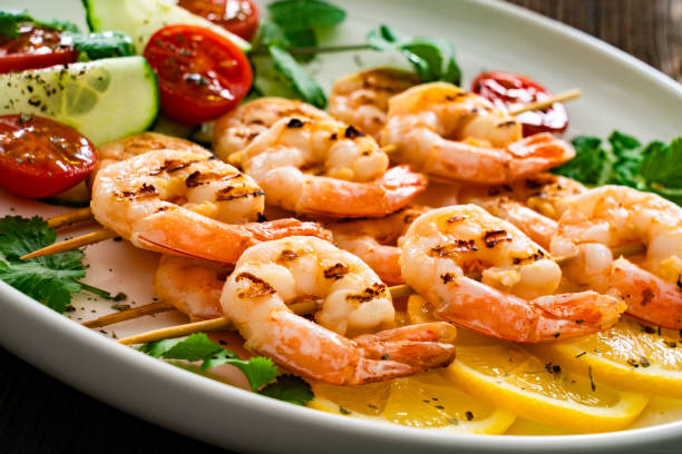 istock Grilled skewer shrimps and fresh vegetables served on on wooden table 2201326574