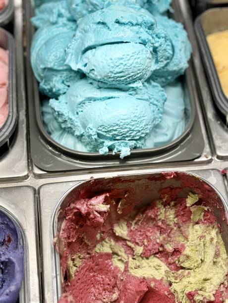 An inviting and delightful selection of colorful and various ice cream flavors is beautifully served in a display case. Close-up