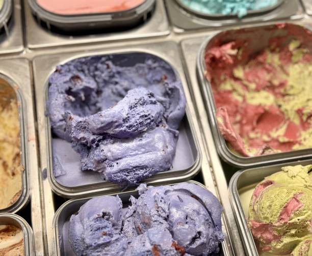 An inviting and delightful selection of colorful and various ice cream flavors is beautifully served in a display case. Close-up