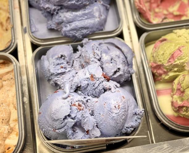 An inviting and delightful selection of colorful and various ice cream flavors is beautifully served in a display case. Close-up