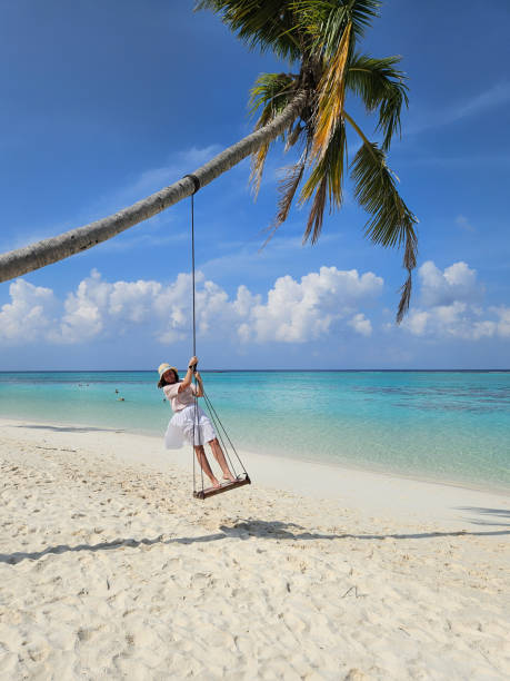 istock Young woman swinging on a tropical beach 2201327810