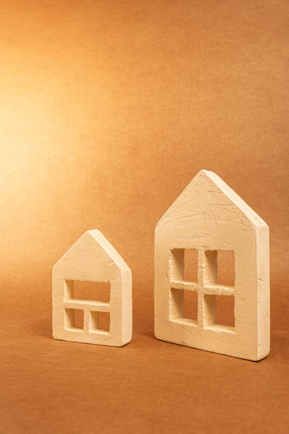 istock Ceramic miniature houses perched on warm brown surface, representing property investment and real estate market concept 2201329573