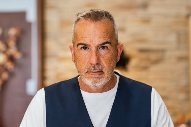 Portrait of a confident mature businessman gazing directly at the camera in a sleek, modern office setting, exuding professionalism and poise
