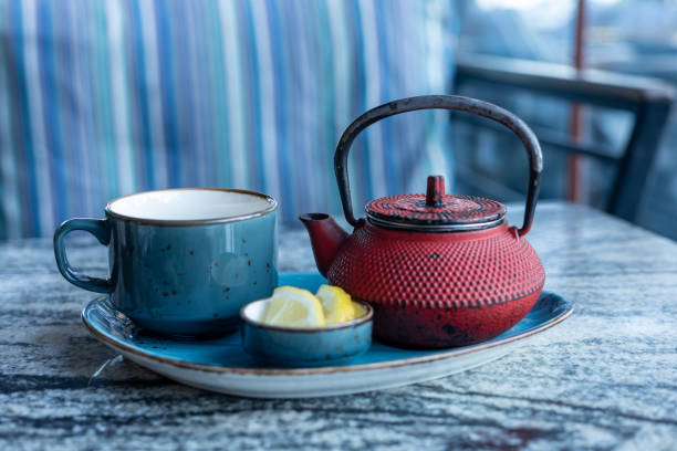 istock Relaxing tea time with a red teapot and blue cup on a marble table 2201330597