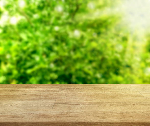 istock Wooden table front abstract blurred tree garden yellow green tone background. 2201331740