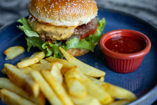 istock Freshly made cheeseburger served with crispy fries on a blue plate 2201332002