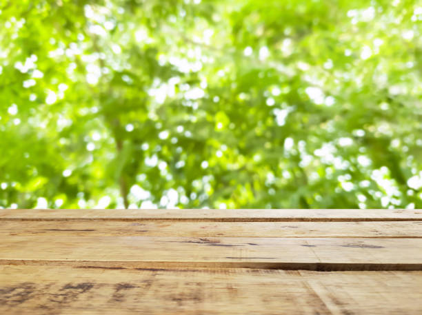 istock Empty wood table top on blur green tree background from garden. 2201332242