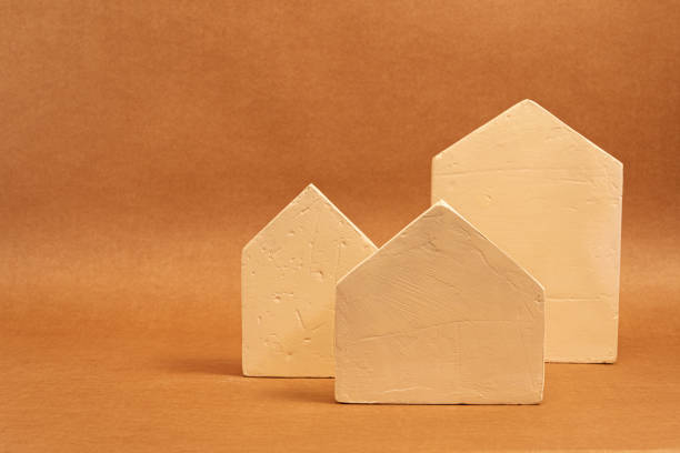 istock Three decorative miniature houses standing on a brown background, representing the concept of real estate market 2201332311