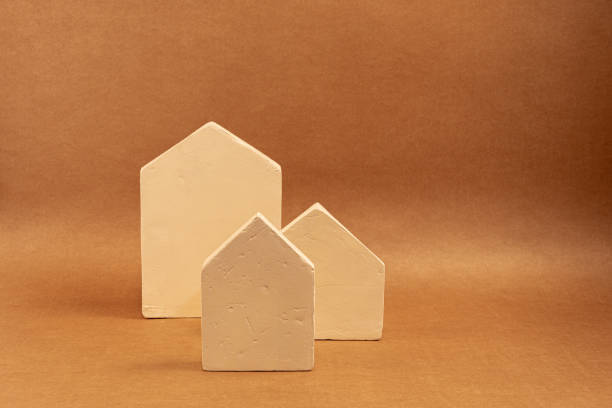 Three miniature houses of different sizes are standing on a brown background, creating a simple yet evocative scene