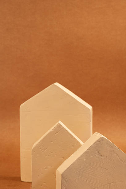 istock Three miniature houses resting on a brown background, representing the complexities of the real estate market and home ownership 2201333024