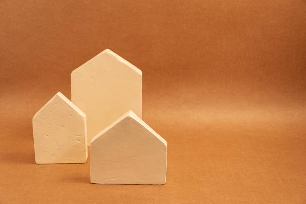 istock Three small, light-colored houses sit on a brown surface, evoking feelings of warmth, home, and simplicity 2201333865
