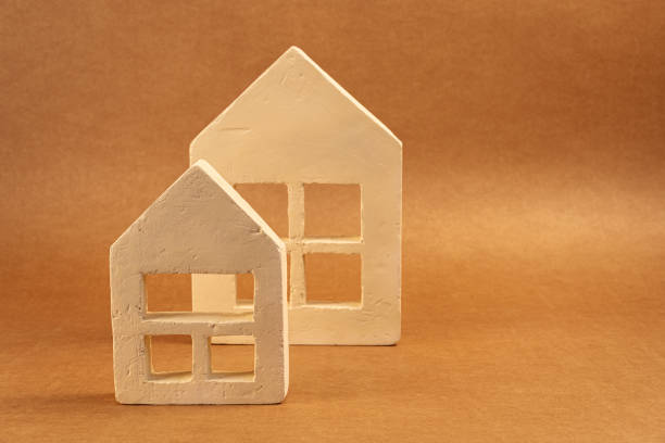 White plaster miniature houses resting on warm brown surface, symbolizing residential property investment and home concept