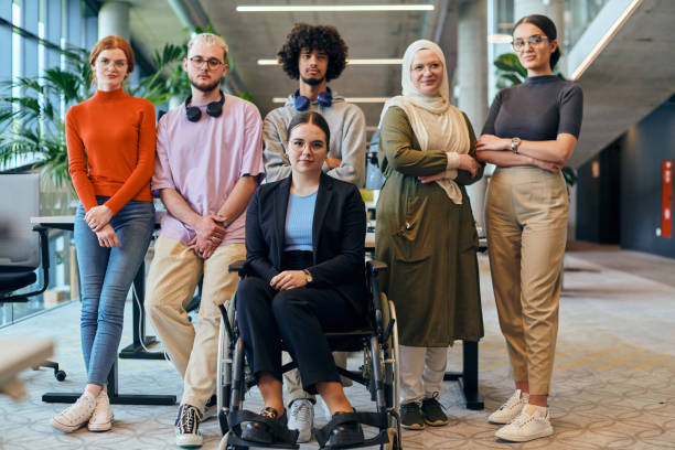 istock In a spacious and modern startup office, a diverse group of business colleagues, including a colleague in a wheelchair, collaborates and interacts, exemplifying inclusivity, diversity, and teamwork in the contemporary corporate world 2201334301