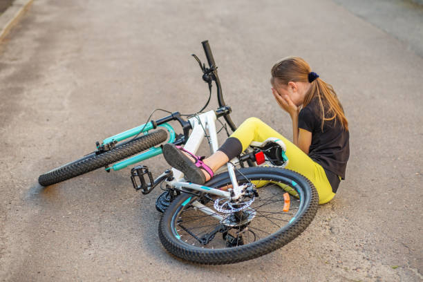 istock Tween girl falls off bicycle and struggles on pavement after losing balance 2201335633