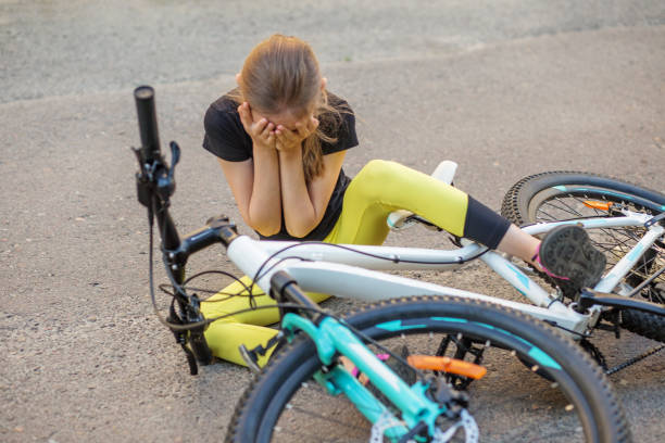 child sitting on the ground with bicycle after falling during cycling activity