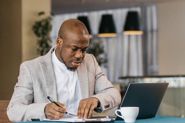 istock Focused Afroamerican man working at a desk in a modern office working on a laptop. 2201346127