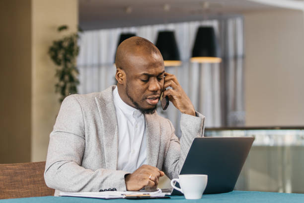 istock Focused Afroamerican man working at a desk in a modern office working on a laptop. 2201346132