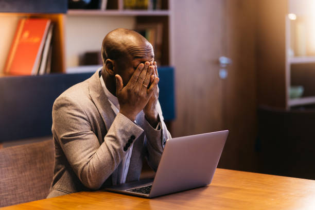 istock Focused Afroamerican man working at a desk in a modern office working on a laptop. 2201346203