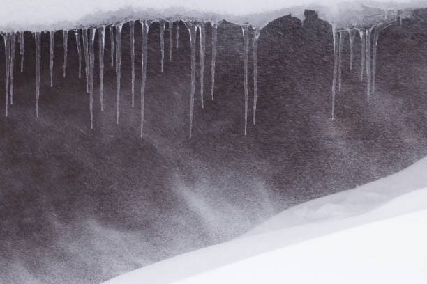 istock Powder snow blowing over icicles hanging from a building roof 2201349166