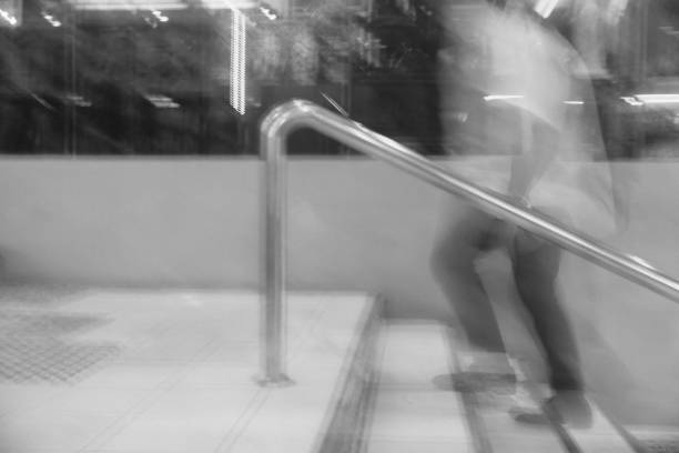 An intentional motion blur photo of a man taking the stairs set in black and white filter