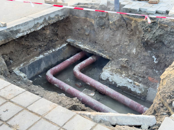 istock Heavy machinery surrounds an excavation site where workers are fixing red underground pipes. The area is marked off with safety tape, indicating active construction 2201363516