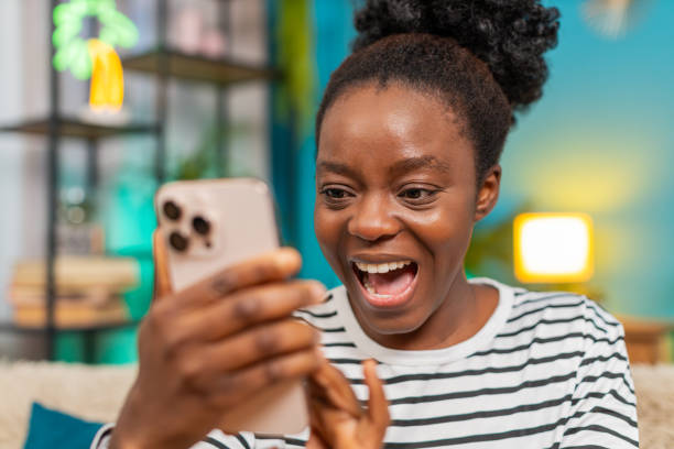 istock African American woman surprised smartphone wide eyes expression unexpected message indoors sofa 2201364857