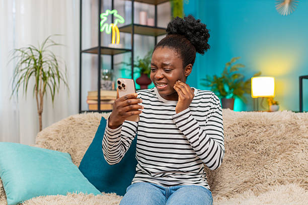 istock African American woman experiencing toothache, looking distressed, using smartphone searching clinic 2201364867